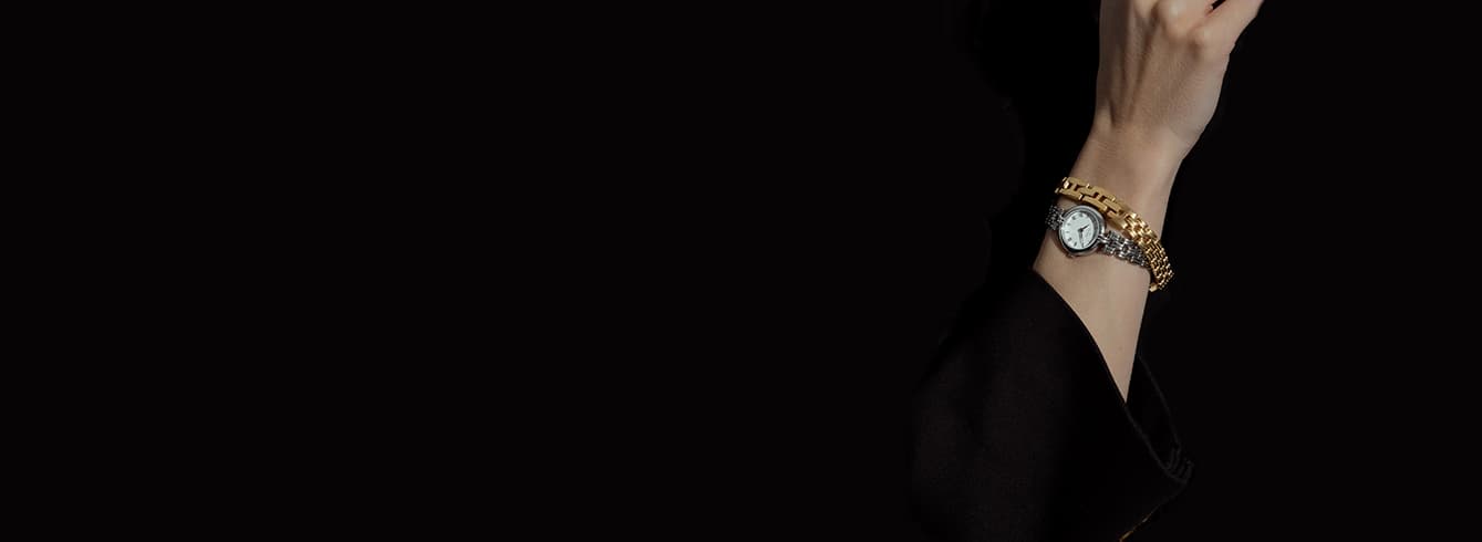 En sølvfarget klokke med svart urskive, blå sekundviser og brun lærreim, som viser klokken som 12:09.